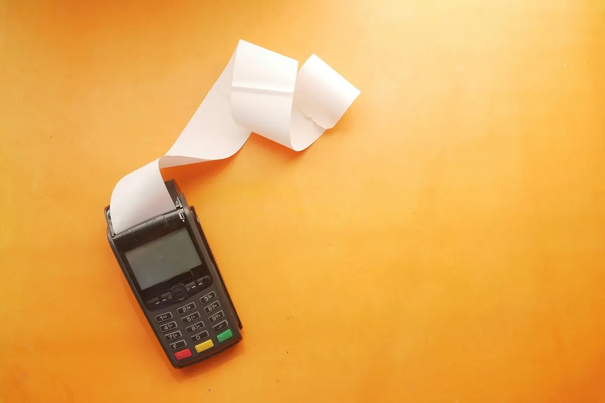 A handheld payment terminal printing a long paper receipt, the kind of till that must keep issuing eTIMS invoices