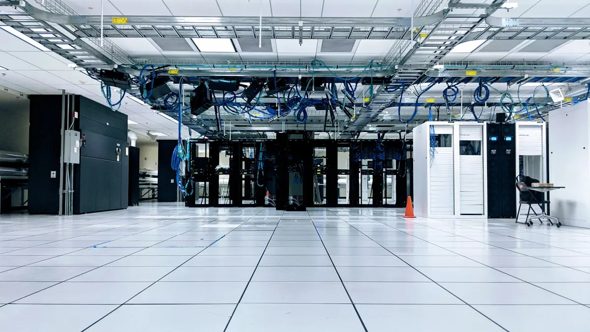 Cold aisle in a colocation data center, rows of racks either side of a raised floor